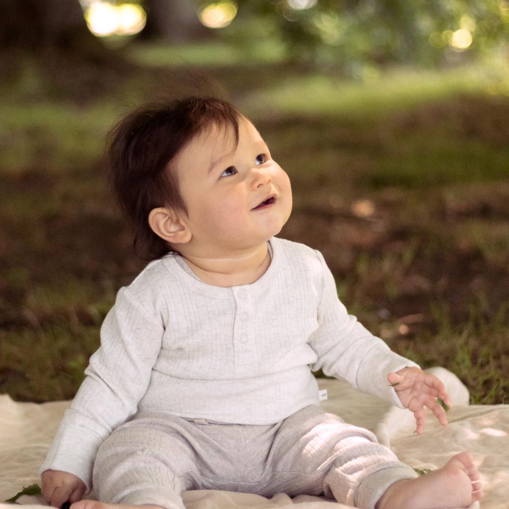 Baby sitting on a blanket in a grassy field