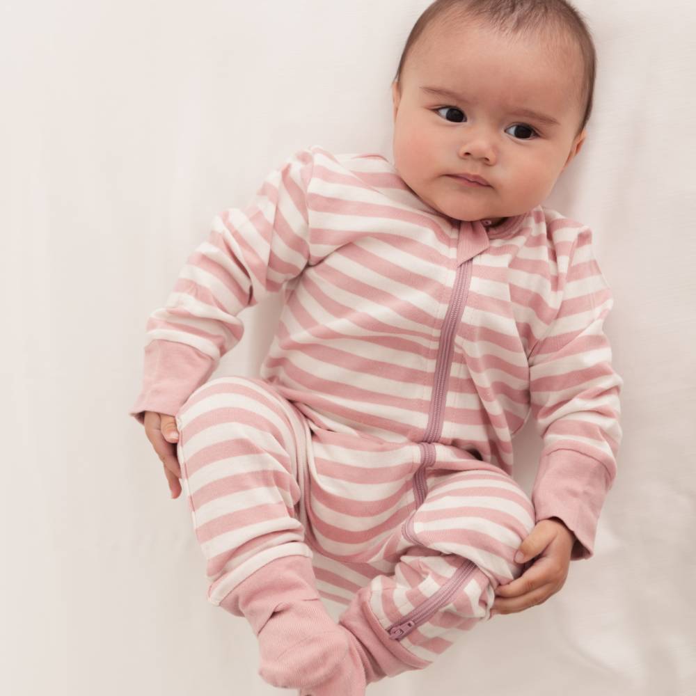 Baby wearing a pink and white striped onesie on a plain background