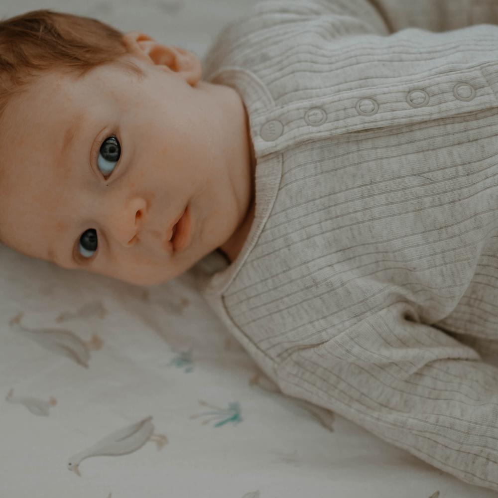 Baby lying on a patterned blanket wearing a textured outfit.