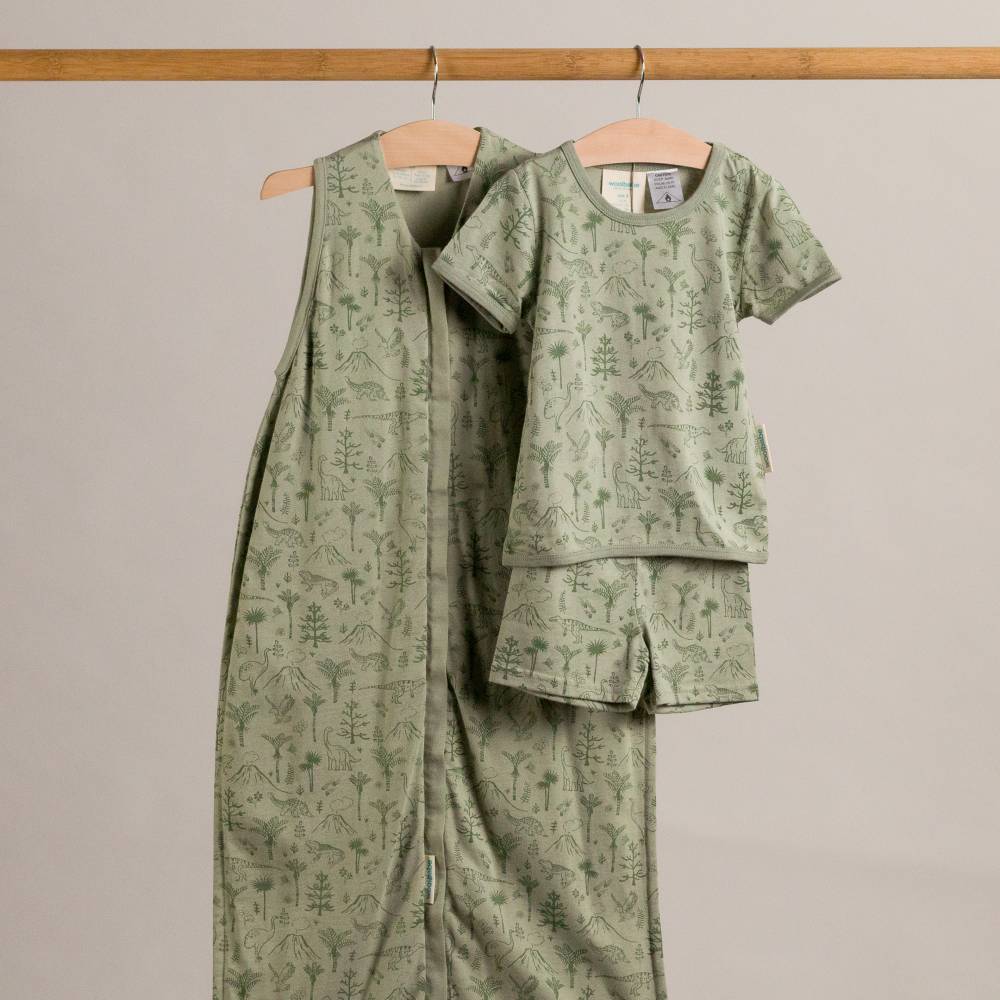 Green patterned outfit on a wooden hanger against a beige background