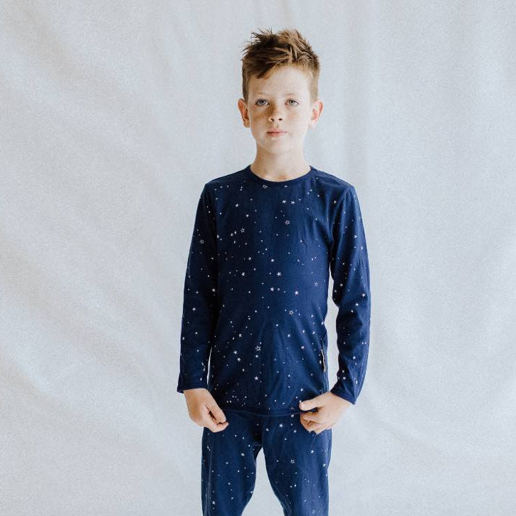 Child wearing a navy blue pajama top with star pattern on a light gray background