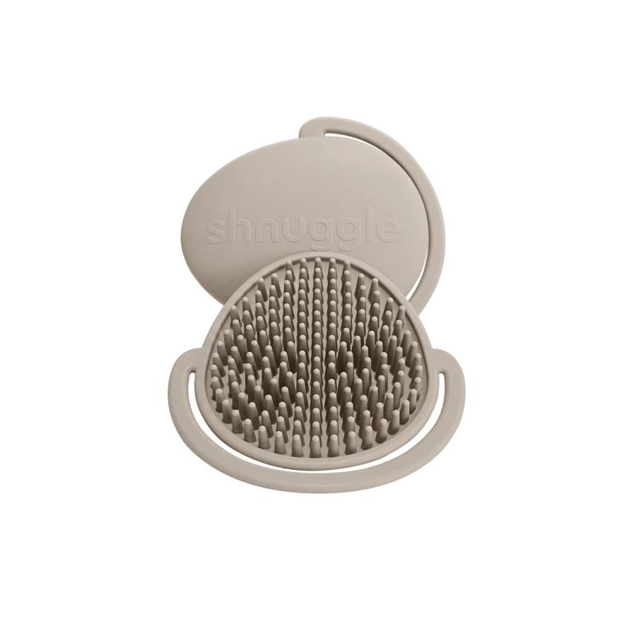 Beige silicone scalp brush with textured surface and smooth lid on a white background, branded 'shnuggle'.